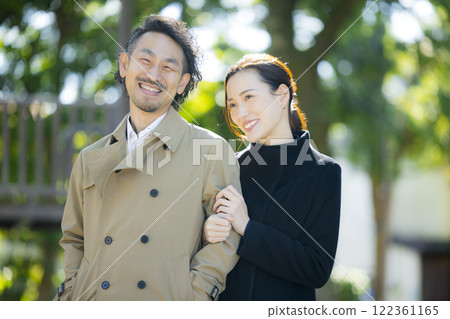 A couple in coats walking down the sidewalk A couple in coats walking down the sidewalk 122361165