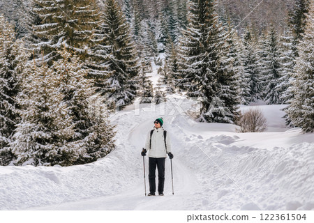 Man Walking with Trekking Poles in Snow Forest 122361504