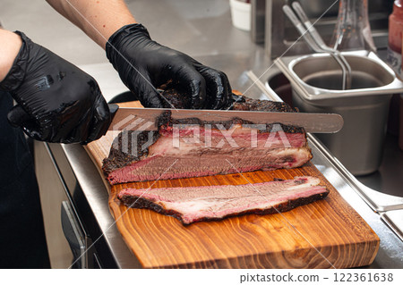Cutting smoked brisket into slices in the kitchen 122361638