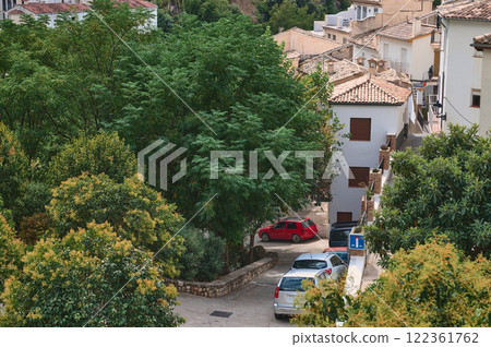 Charming Mediterranean village view with trees, houses, and parked vehicles Charming Mediterranean village view with trees, houses, and parked vehicles 122361762