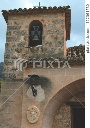 Stone church bell tower and decorative details under a cloudy sky Stone church bell tower and decorative details under a cloudy sky 122361780