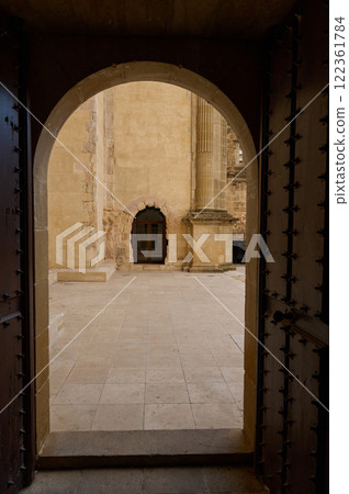 View of a stone courtyard seen through an open traditional arched door View of a stone courtyard seen through an open traditional arched door 122361784