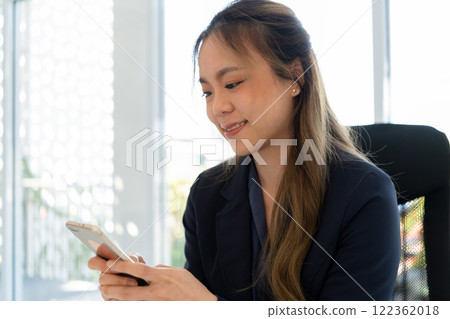 Businesswoman sitting at desk on couch in workplace or at home working on laptop and analyzing data on charts and graphs and writing on papers to make business plan and strategies for company. 122362018