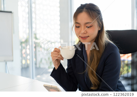 Businesswoman sitting at desk on couch in workplace or at home working on laptop and analyzing data on charts and graphs and writing on papers to make business plan and strategies for company. Businesswoman sitting at desk on couch in workplace or at home working on laptop and analyzing data on charts and graphs and writing on papers to make business plan and strategies for company. 122362019
