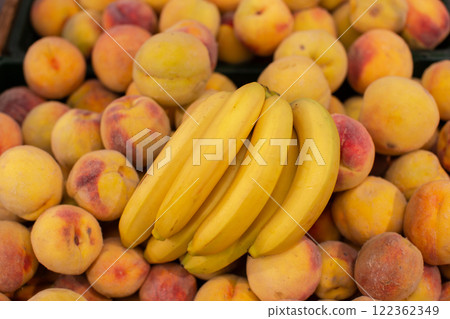 A branch of ripe bananas and peaches on the shop window. A branch of ripe bananas and peaches on the shop window. 122362349