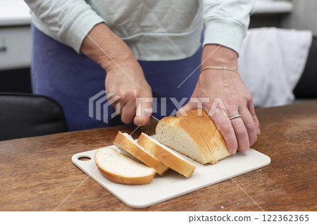 Hands cutting a loaf with a knife. Make a breakfast. Hands cutting a loaf with a knife. Make a breakfast. 122362365