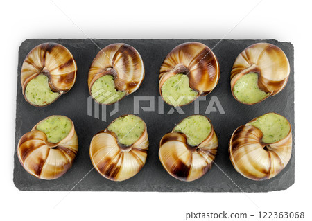escargot snail filled with garlic and parsley butter on a stone board isolated on white background. Top view. Flat lay 122363068