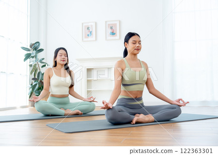 Front view of beautiful Asian women with exercise clothes do yoga posture like meditation in room with day light. Front view of beautiful Asian women with exercise clothes do yoga posture like meditation in room with day light. 122363301