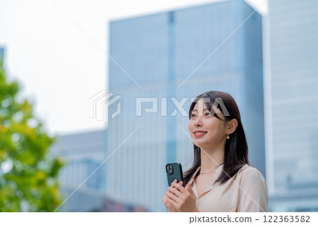 日本婦女拿著智慧型手機，背景是一棟建築物 122363582