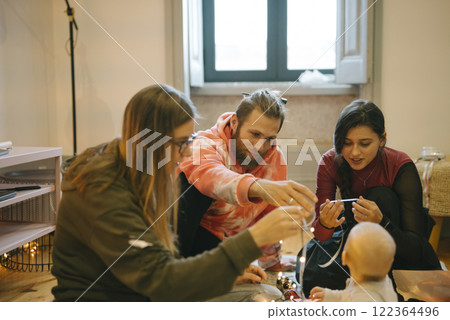 A beautiful candid family moment featuring a baby, friends, and joyous interactions all around 122364496