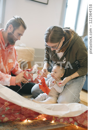 Joyful Family Moment Unwrapping Gifts Together with Their Cherished Baby this Holiday Season 122364558
