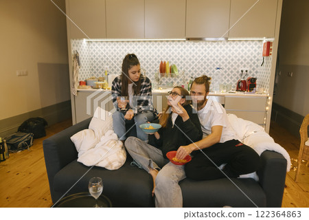 A group of close friends enjoying a cozy and delightful evening gathered together on a couch A group of close friends enjoying a cozy and delightful evening gathered together on a couch 122364863