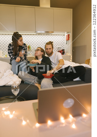 A group of friends enjoying a delightful and cozy movie night together in their home setting A group of friends enjoying a delightful and cozy movie night together in their home setting 122364912