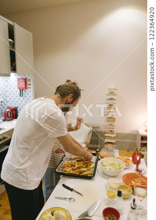 A couple is happily cooking together in their cozy, warm kitchen, enjoying the moment 122364920