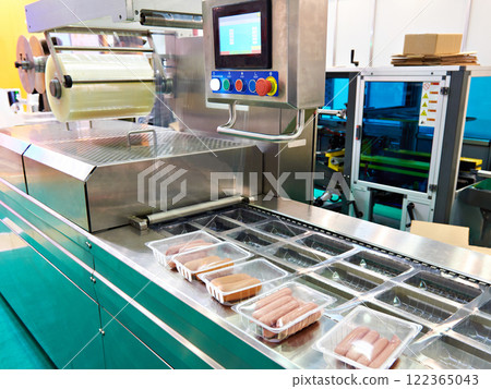 Plastic containers with sausages on conveyor at food factory Plastic containers with sausages on conveyor at food factory 122365043