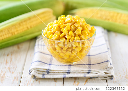 Canned food maize in a clear glass bowl on a white kitchen table, selective focus. 122365132
