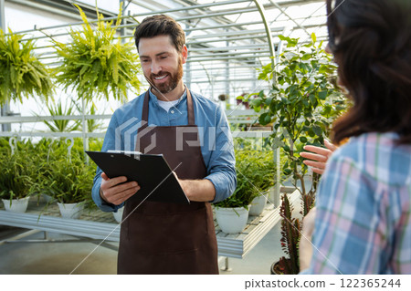 Greenhouse worker talking to a supervisor of quality control Greenhouse worker talking to a supervisor of quality control 122365244