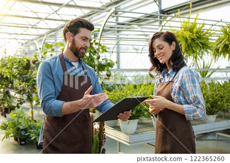 Two workers in a greenhouse looking positive and contented 122365260