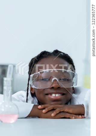Scientist hiding behind table with flask analyzing sample conducting research in laboratory 122365777