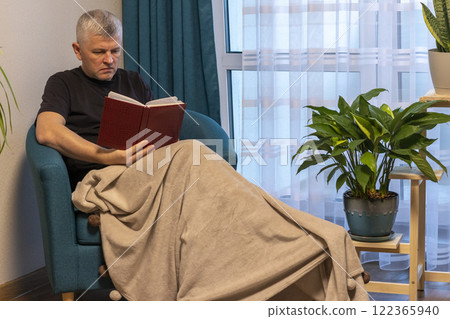 Man sitting in the cozy corner in the apartment on comfortable arm chair. 122365940
