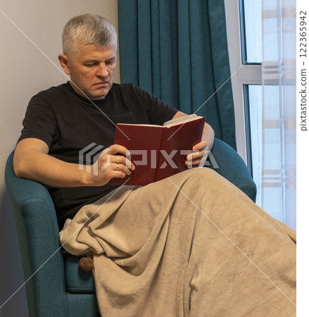 Man sitting in the cozy corner in the apartment on comfortable arm chair. Man sitting in the cozy corner in the apartment on comfortable arm chair. 122365942