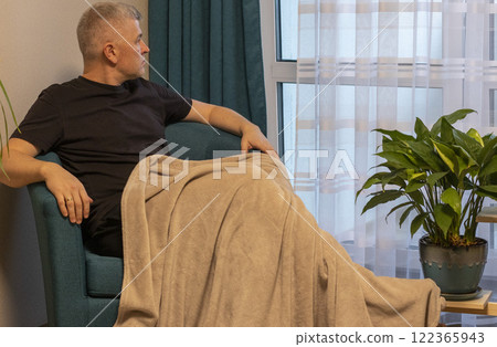 Man sitting in the cozy corner in the apartment on comfortable arm chair. Man sitting in the cozy corner in the apartment on comfortable arm chair. 122365943