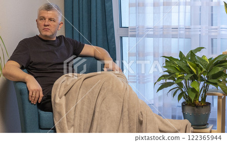 Man sitting in the cozy corner in the apartment on comfortable arm chair. 122365944