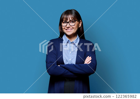Portrait mature business woman with crossed arms on blue background Portrait mature business woman with crossed arms on blue background 122365982