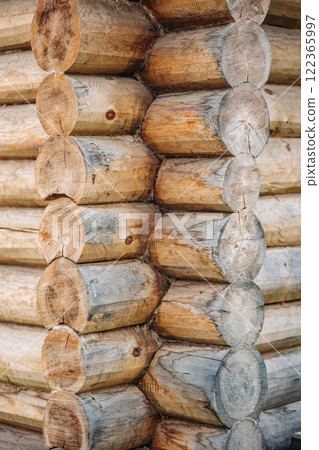 Rustic log cabin corner revealing precise interlocking woodwork, displaying traditional carpentry skills using raw, weathered timber materials 122365997
