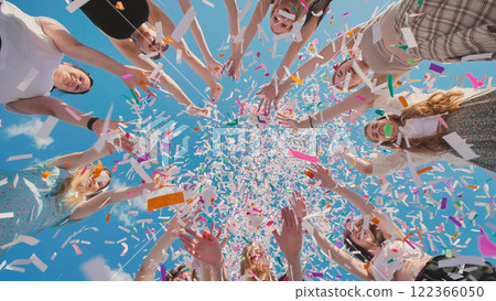 High school graduates joyfully tossing vibrant confetti in the air to celebrate their summer graduation High school graduates joyfully tossing vibrant confetti in the air to celebrate their summer graduation 122366050