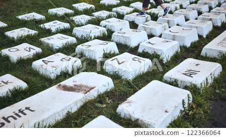 Child walking on giant keyboard keys installed in a park, blending technology with nature 122366064