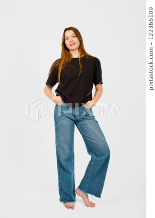 Woman confidently poses with hands in pockets while wearing casual outfit at indoor studio Woman confidently poses with hands in pockets while wearing casual outfit at indoor studio 122366109