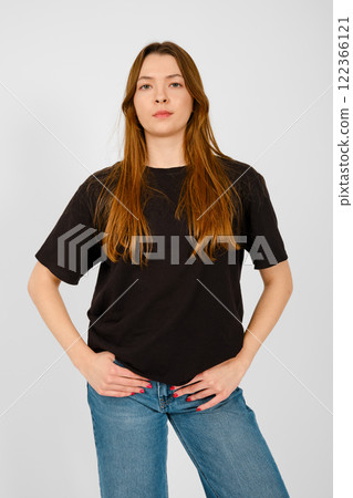 Confident young woman posing against a plain background in casual attire with long hair 122366121