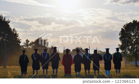 Students in graduation gowns celebrating by tossing their hats in the air 122366125