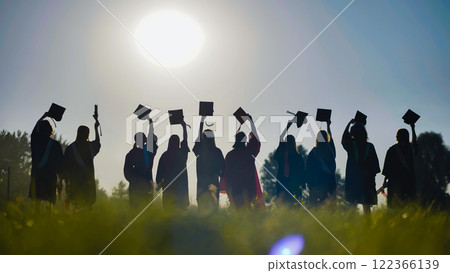 High school graduates silhouetted at sunset, tossing their caps in celebration High school graduates silhouetted at sunset, tossing their caps in celebration 122366139