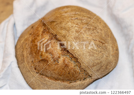 Shot of the freshly baked loaf of home made rye bread on the linen cloth Shot of the freshly baked loaf of home made rye bread on the linen cloth 122366497