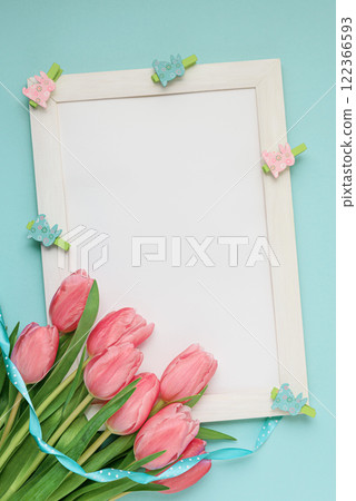 A vibrant Easter greeting card featuring a delicate arrangement of pink tulips, a soft blue ribbon, and adorable bunny-shaped clothespins. Perfect for spreading joy and warmth this Easter season. A vibrant Easter greeting card featuring a delicate arrangement of pink tulips, a soft blue ribbon, and adorable bunny-shaped clothespins. Perfect for spreading joy and warmth this Easter season. 122366593