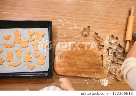 raw gingerbread dough for cookies on baking tray and cookie cutters on table, top view 122366618
