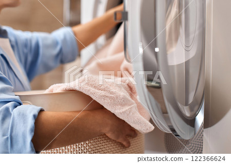 female hands put pastel cotton towel in automatic washing machine female hands put pastel cotton towel in automatic washing machine 122366624