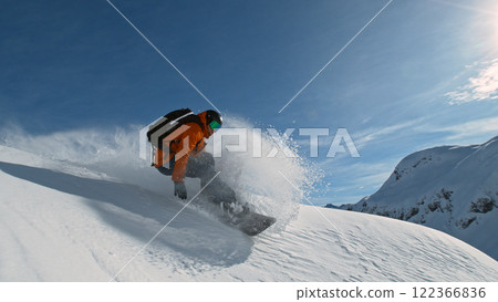 Snowboard rider riding down fresh powder during sunny day , Alpine scenery 122366836