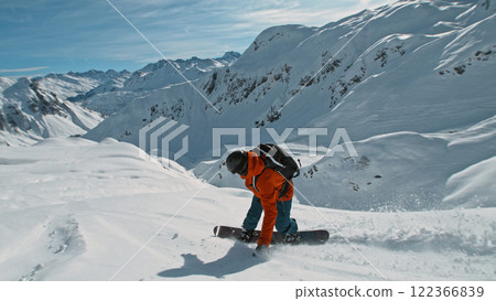 Snowboard rider riding down fresh powder during sunny day , Alpine scenery 122366839