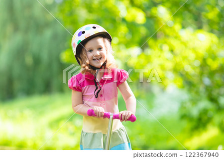 Little girl riding a colorful scooter Little girl riding a colorful scooter 122367940