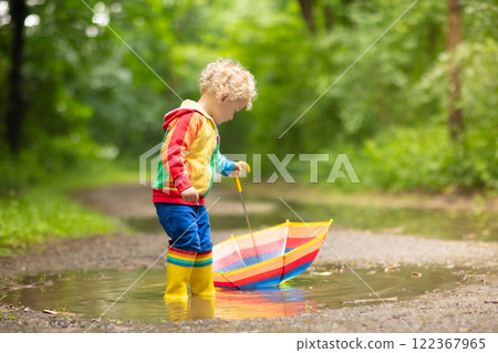Child playing in the rain under umbrella Child playing in the rain under umbrella 122367965