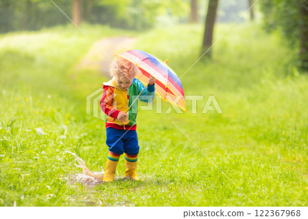 Child playing in the rain under umbrella Child playing in the rain under umbrella 122367968