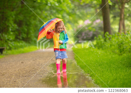 Child playing in the rain with umbrella Child playing in the rain with umbrella 122368063