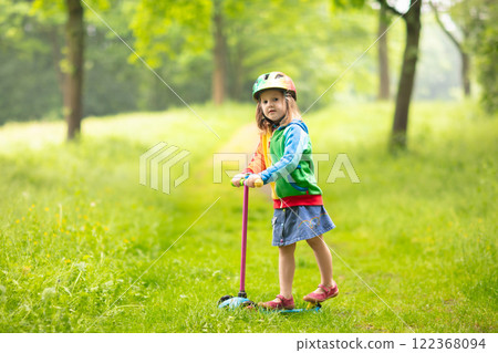Litte girl riding scooter. Child playing outdoor. 122368094