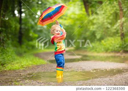 Child playing in the rain under umbrella Child playing in the rain under umbrella 122368300