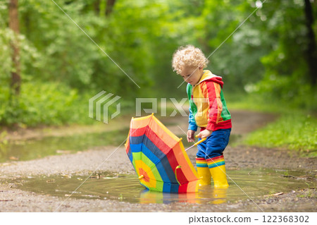 Child playing in the rain under umbrella Child playing in the rain under umbrella 122368302