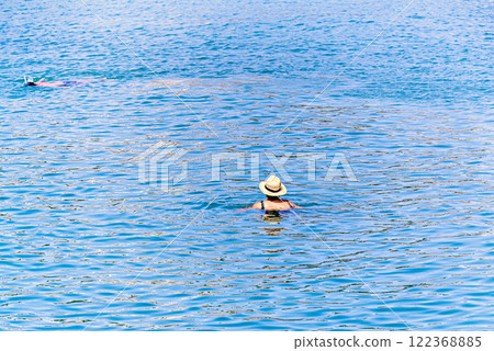 Woman with straw hat relaxing in the water of Peniscola beach, Castellon, Spain Woman with straw hat relaxing in the water of Peniscola beach, Castellon, Spain 122368885