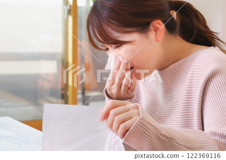 Young Asian woman painfully blowing her runny nose 122369116